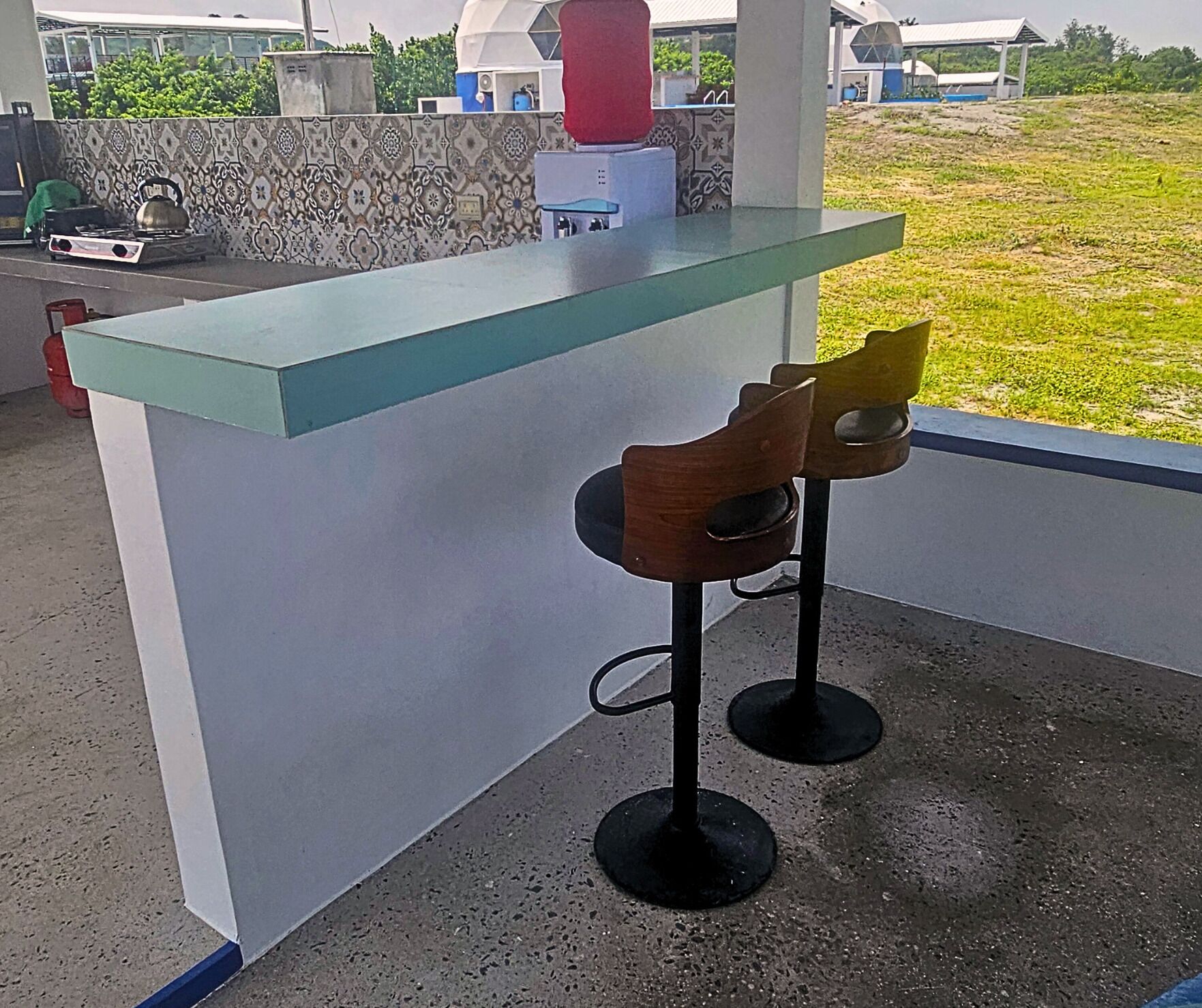 A bar area with a glass counter and two wooden bar stools.