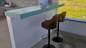 A bar area with a glass counter and two wooden bar stools.