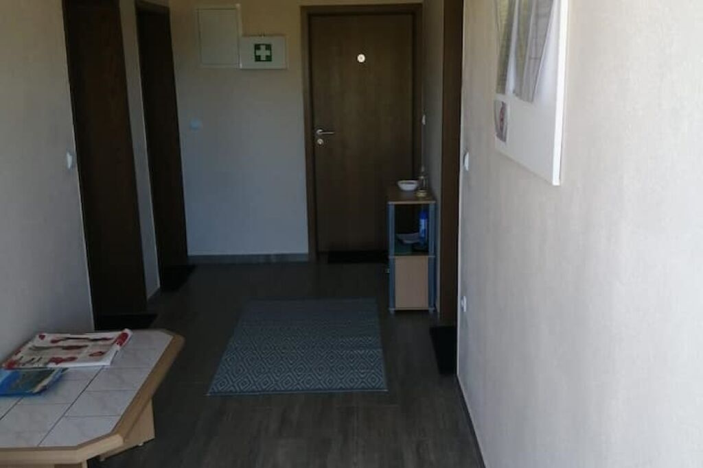 Un couloir avec une porte en bois, une petite table avec des magazines et un tapis à motifs.
