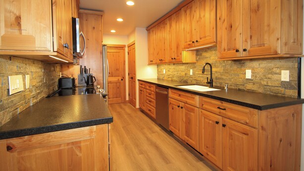 A modern kitchen with wooden cabinets, a black countertop, and a stone backsplash. - Tamarack #39: 2  BR, 2.5  BA Condominium in Mammoth Lakes, Sleeps 8 (Mammoth Lakes)