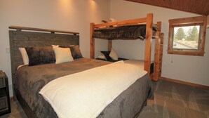 A bedroom with a bunk bed, a large bed with a headboard, and a window with a view of trees. - Tamarack #39: 2  BR, 2.5  BA Condominium in Mammoth Lakes, Sleeps 8 (Mammoth Lakes)