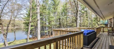 A wooden deck with a view of a lake and forest.