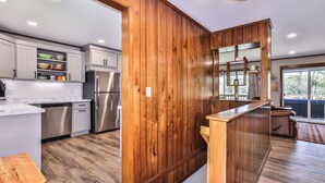 A modern kitchen with wooden accents, stainless steel appliances, and a view to the outside.