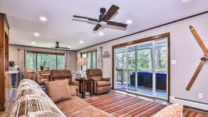 A spacious living room with a large sectional sofa, two armchairs, a coffee table, and a ceiling fan. There is a sliding glass door leading to an outdoor deck.
