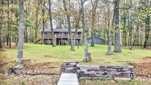 A two-story cabin with a deck, surrounded by a forest.