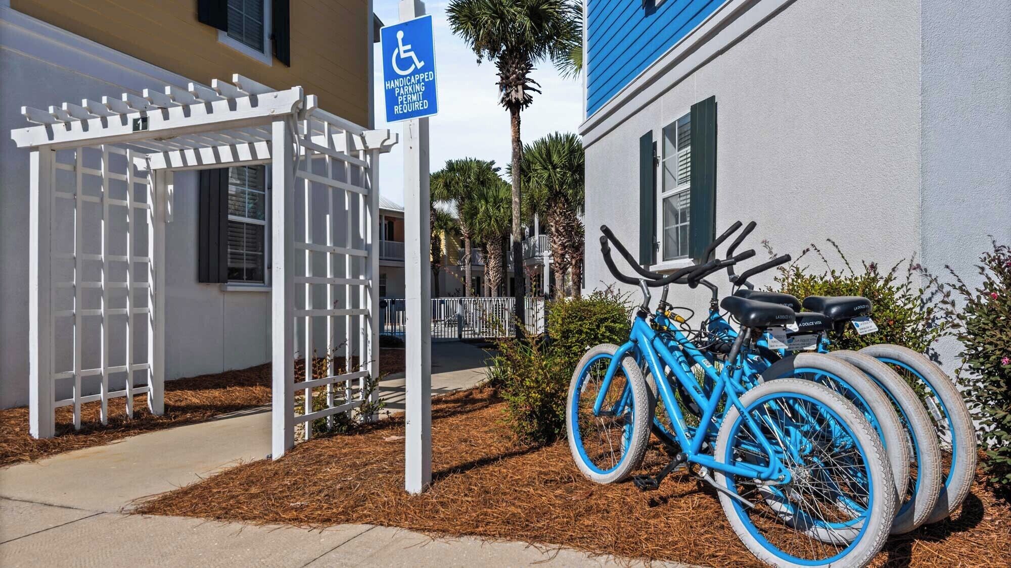 A handicap parking sign, a white pergola, and a blue bicycle with a lock.