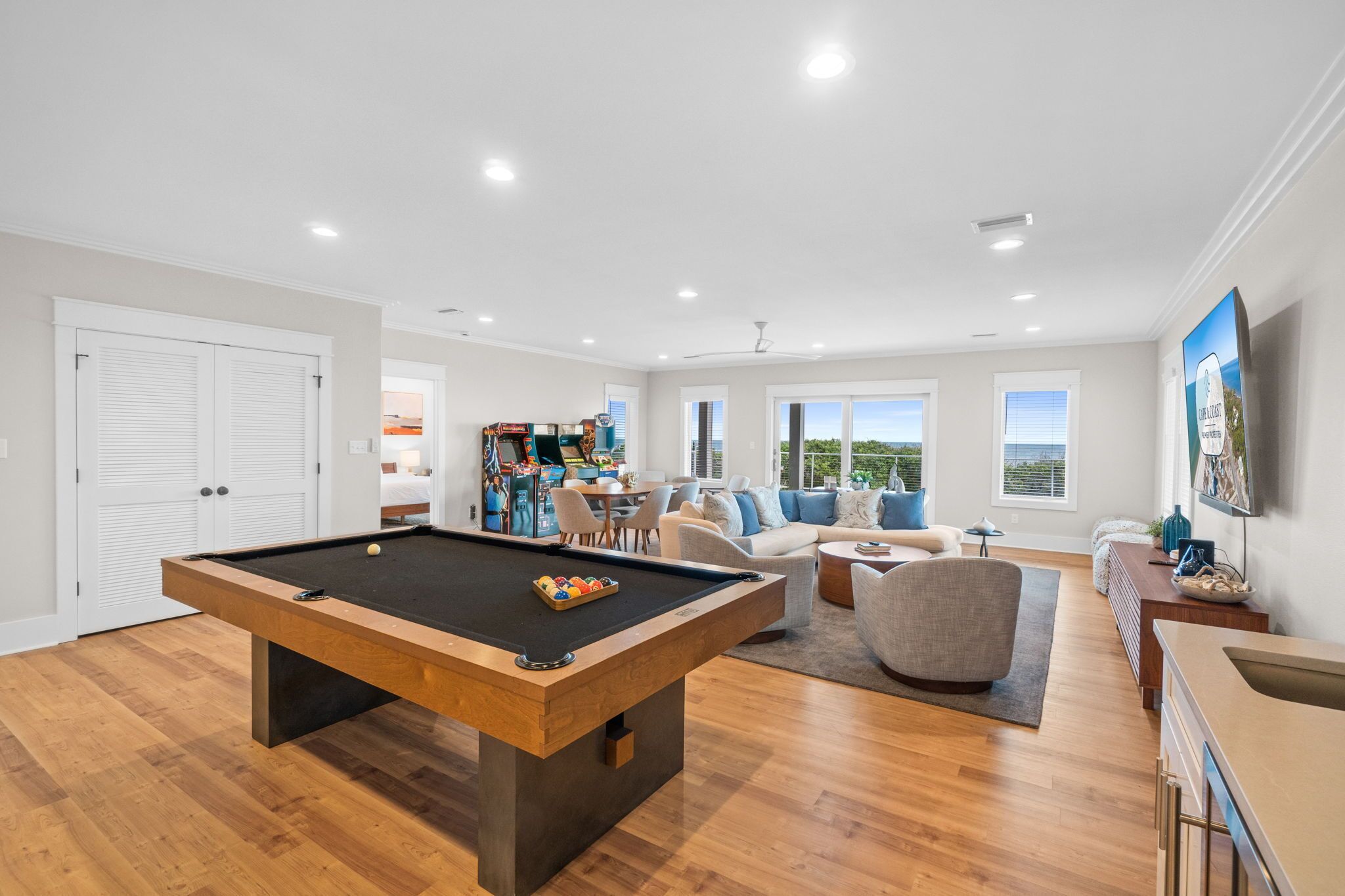 Un salon moderne avec une table de billard, un ensemble de canapés et un téléviseur.