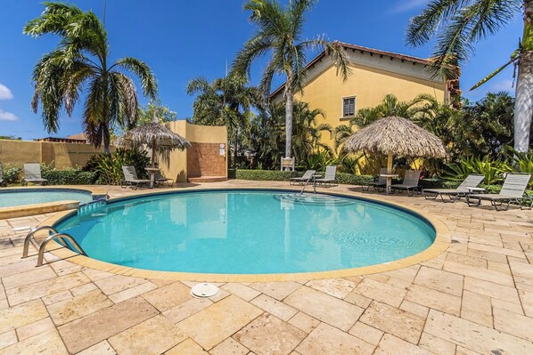 A swimming pool with lounge chairs and palm trees.