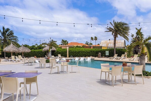 A poolside area with lounge chairs, tables, and umbrellas.