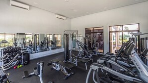 Une salle de sport équipée de divers appareils d’exercice, dotée de grandes fenêtres et d’un système de climatisation.