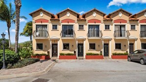Une rangée de maisons de ville avec des balcons, une allée pavée et une voiture garée.