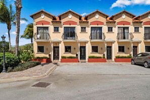 A row of townhouses with balconies, a paved driveway, and a parked car. - Private Pool & Backyard Oasis near Catalina Beach (Noord)