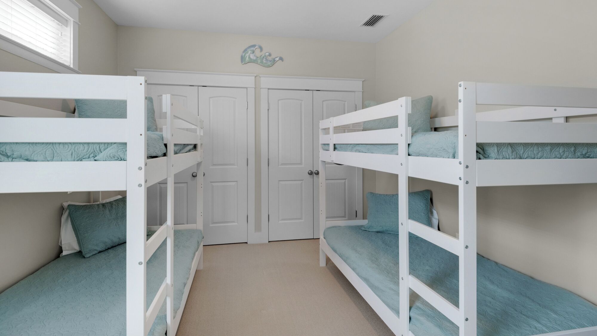 A bedroom with two bunk beds, a closet with double doors, and a decorative wall piece.