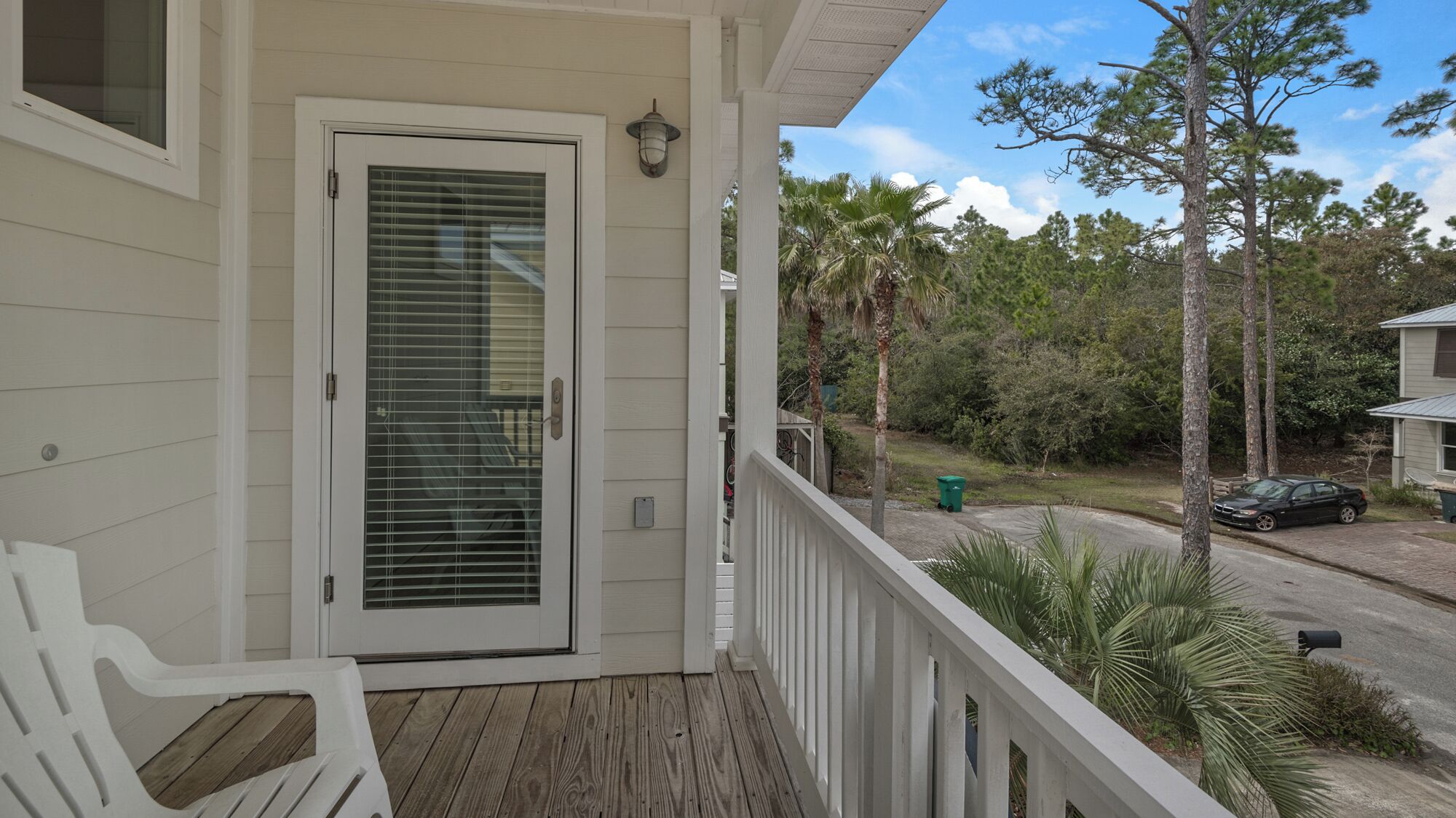 A wooden porch with a white door and a small outdoor seating area.