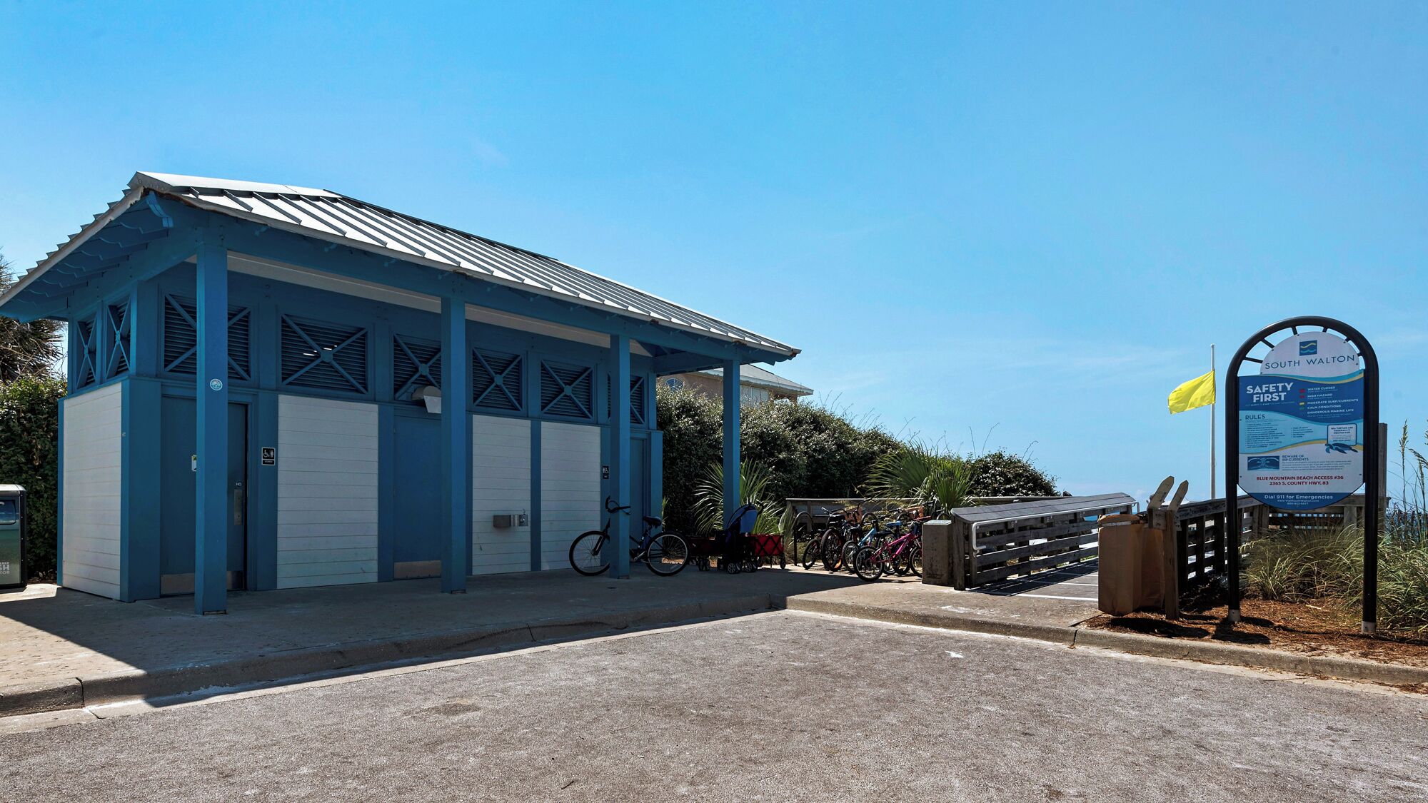 Um edifício azul com entrada coberta, uma placa e bicicletas estacionadas na frente.