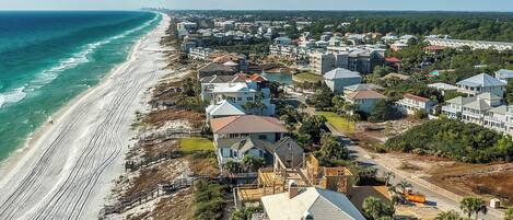 Vista aérea de una zona residencial costera con casas, una playa y un muelle.