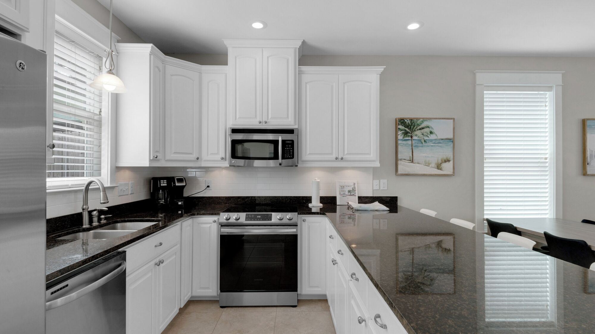 A modern kitchen with white cabinets, stainless steel appliances, and a granite countertop.