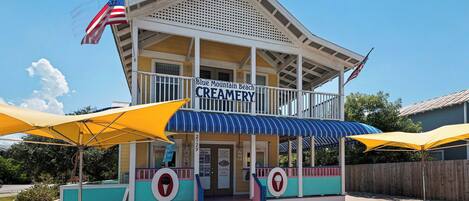 A creamery with a blue awning and a sign that reads 'Blue Mountain Beach Creamery.'
