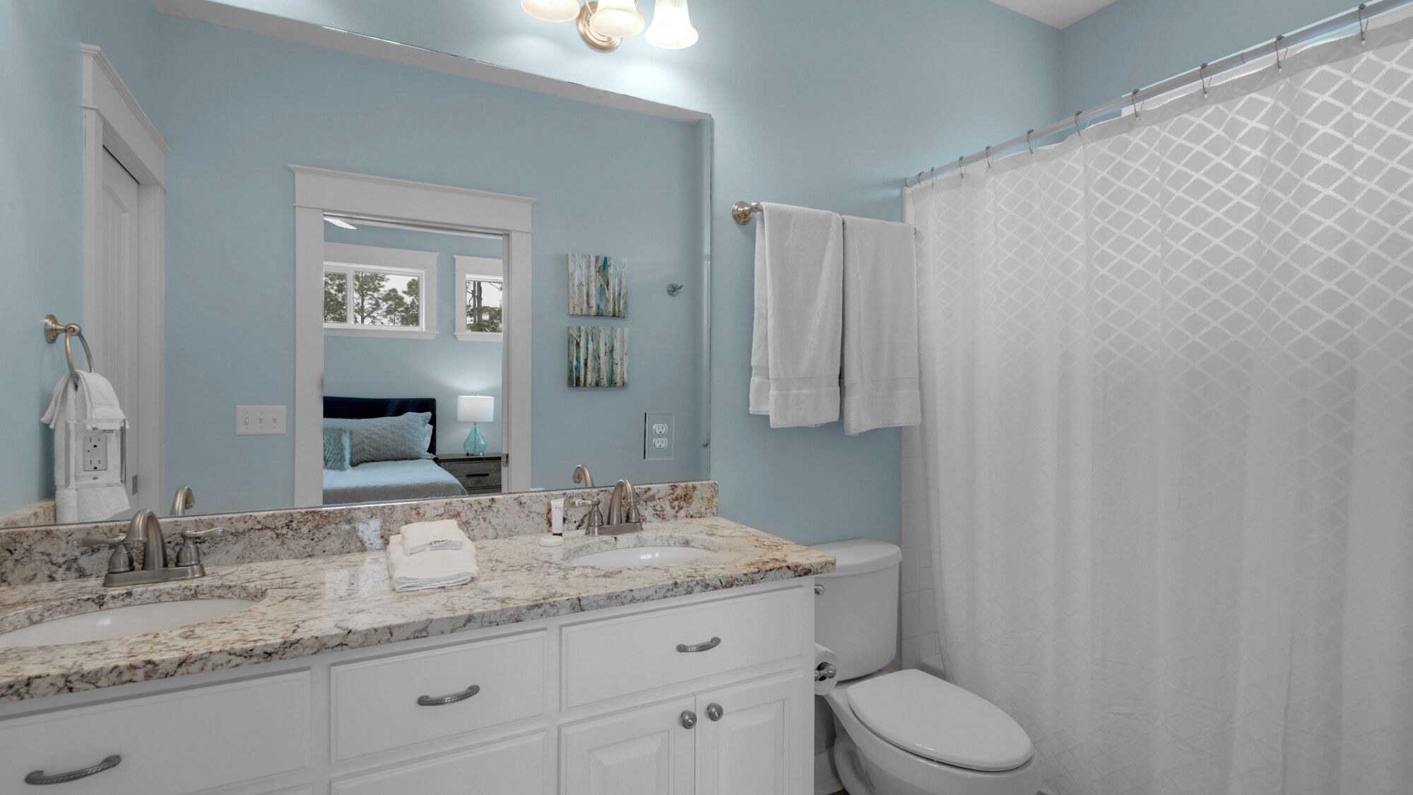 A bathroom with a marble countertop, a white toilet, and a shower curtain.