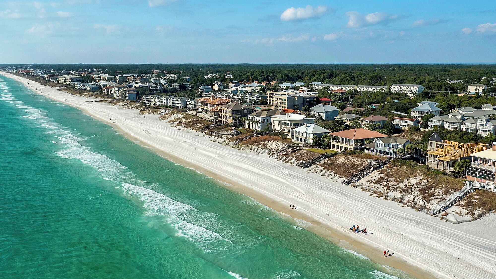 A coastal residential area with beachfront properties, a sandy beach, and a clear view of the ocean.