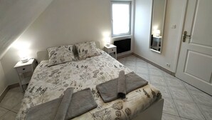 A bedroom with a bed, a nightstand, a window, a mirror, and a door. - Le 11 de Colmar (Colmar)