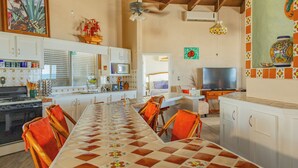 Una cocina amplia con una larga mesa de comedor, sillas y un televisor.