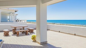 Una terraza con vista al mar, que incluye una mesa, sillas y una planta en maceta.
