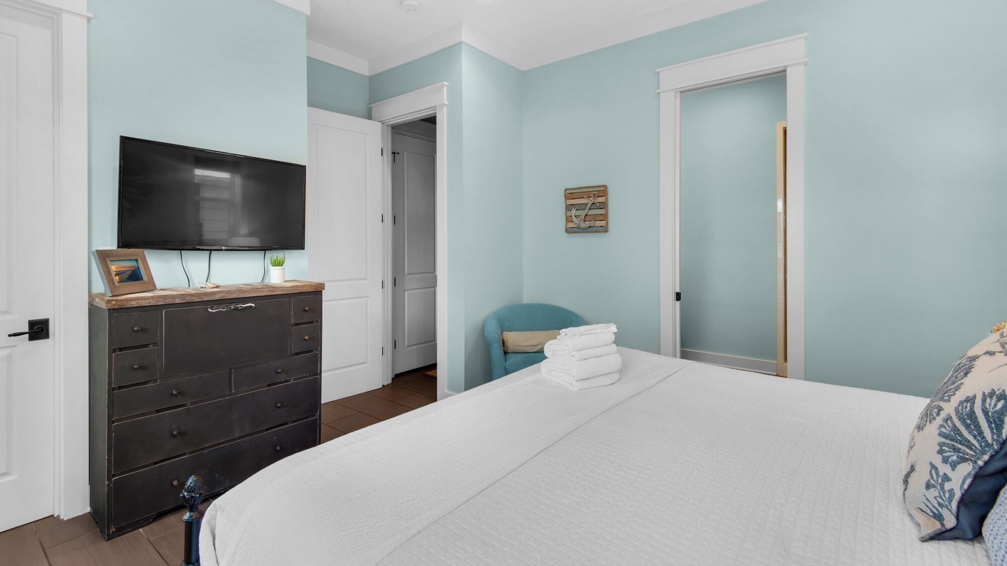 A bedroom with a bed, a dresser, a television, and a chair.