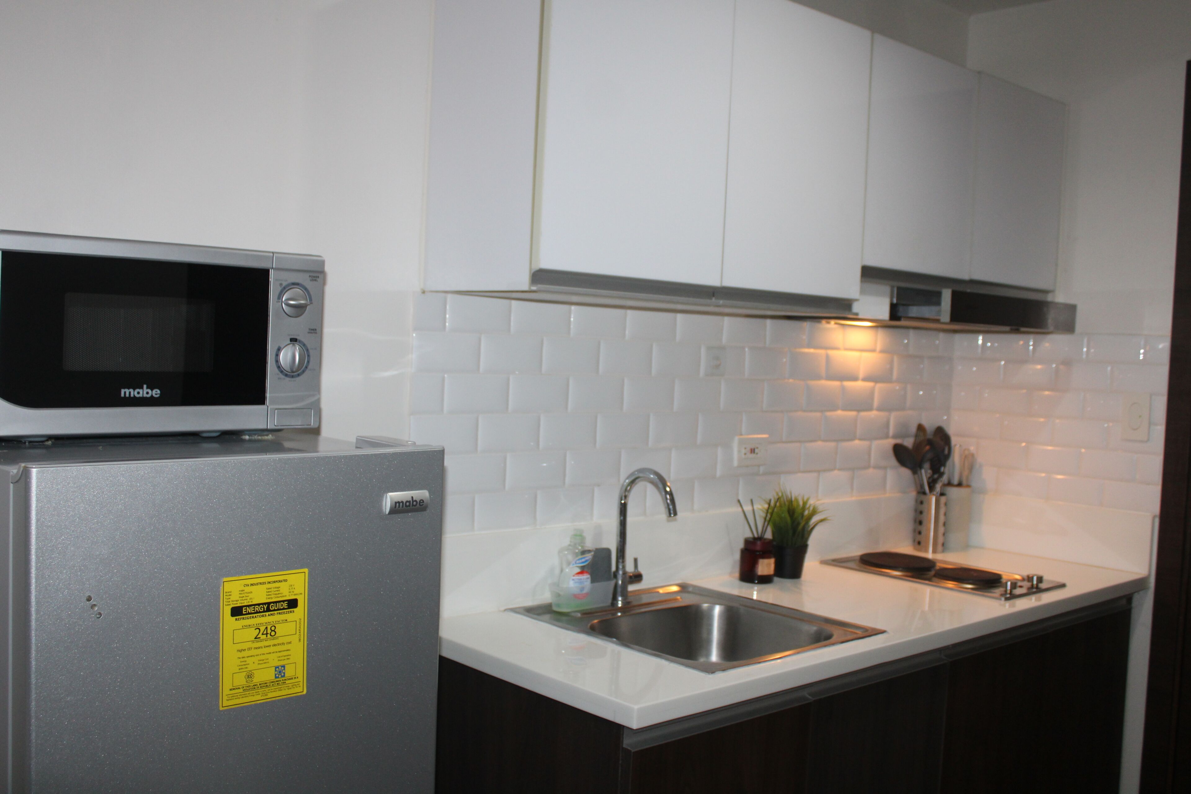 A kitchen with a microwave, refrigerator, sink, and cabinets.