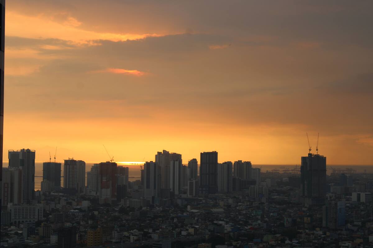 A city skyline at sunset with high-rise buildings and a dense urban area.