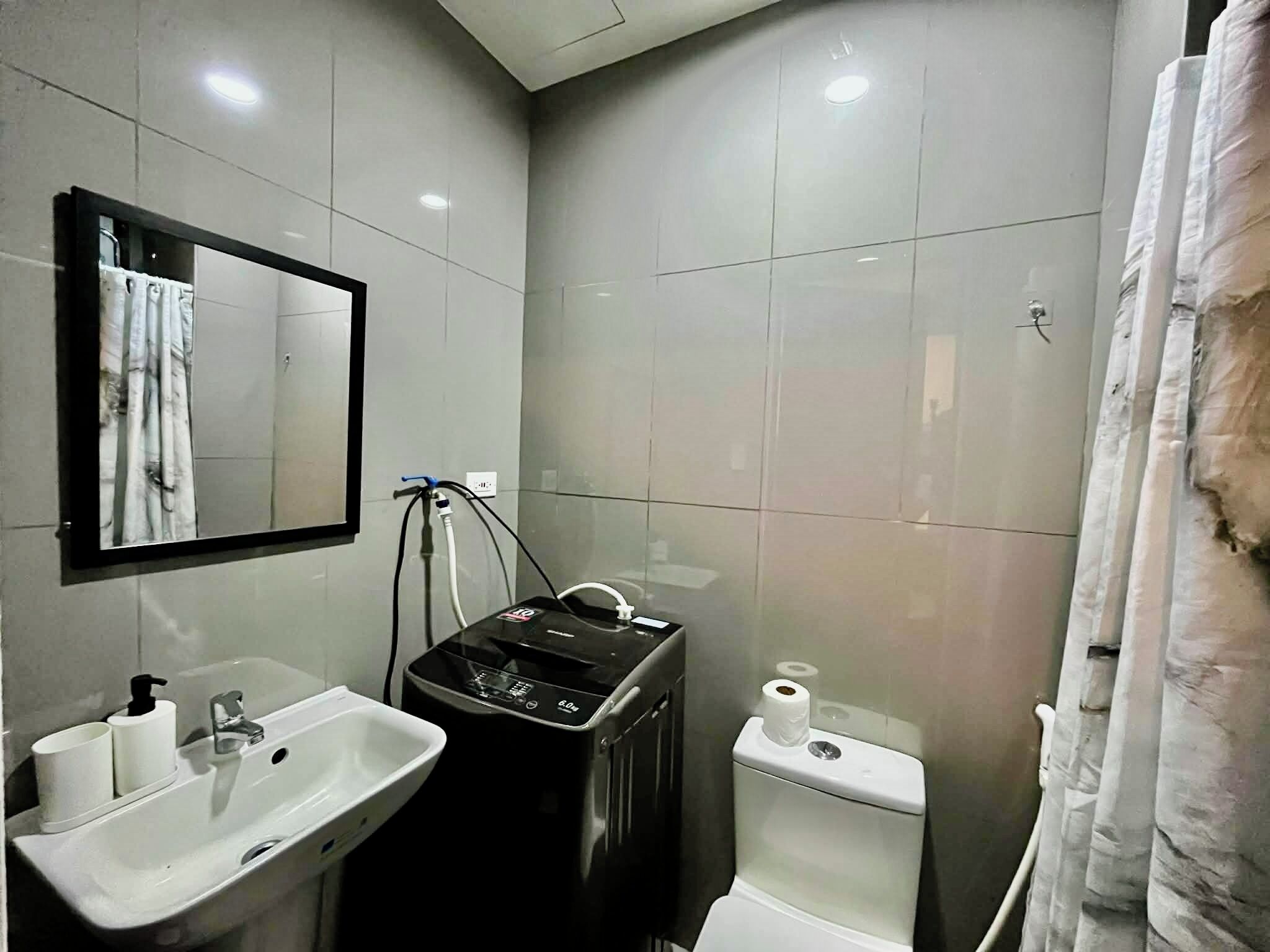 A bathroom with a sink, mirror, toilet, and a black device possibly for water filtration.