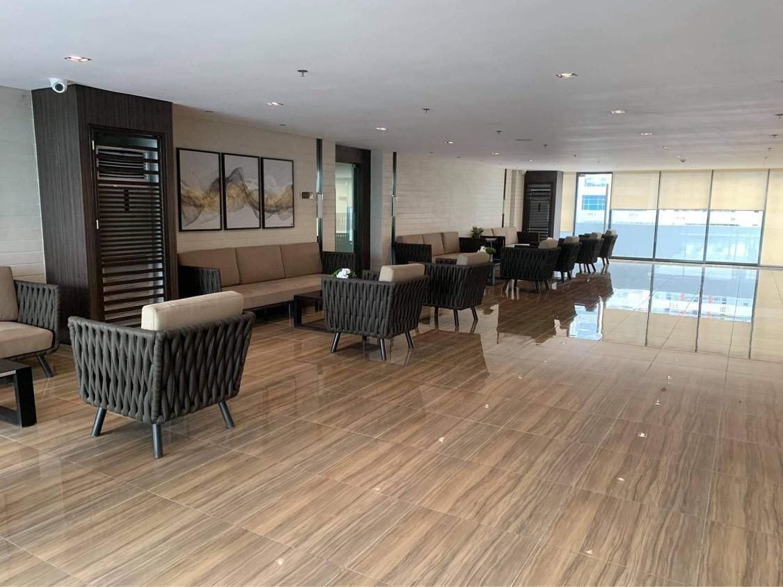 Een ruime lobby met een modern design, met diverse zithoeken, een groot raam met uitzicht en een gepolijste vloer.