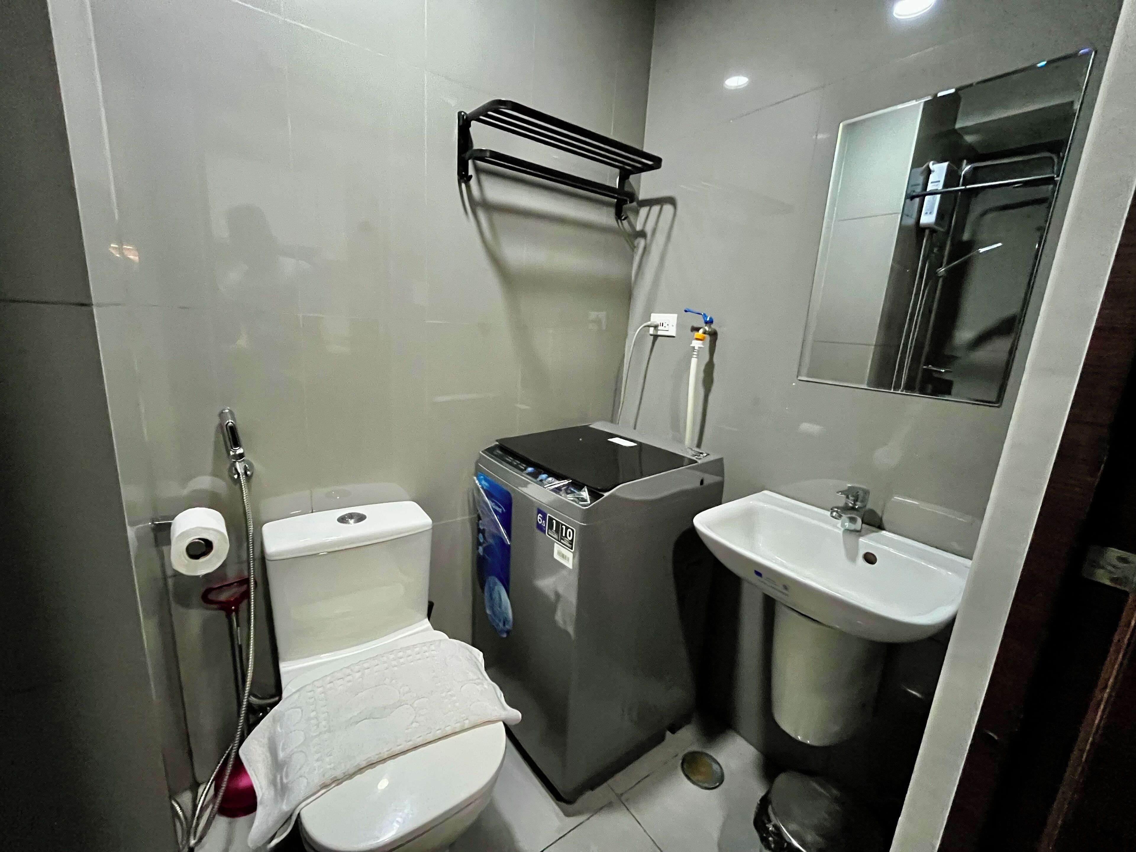 A compact bathroom with a toilet, a small sink, a mirror, and a heater.