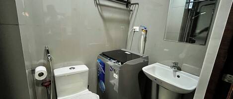 A compact bathroom with a toilet, a small sink, a mirror, and a heater.