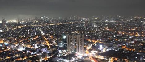 A nighttime cityscape with dense urban development, high-rise buildings, and illuminated streets.