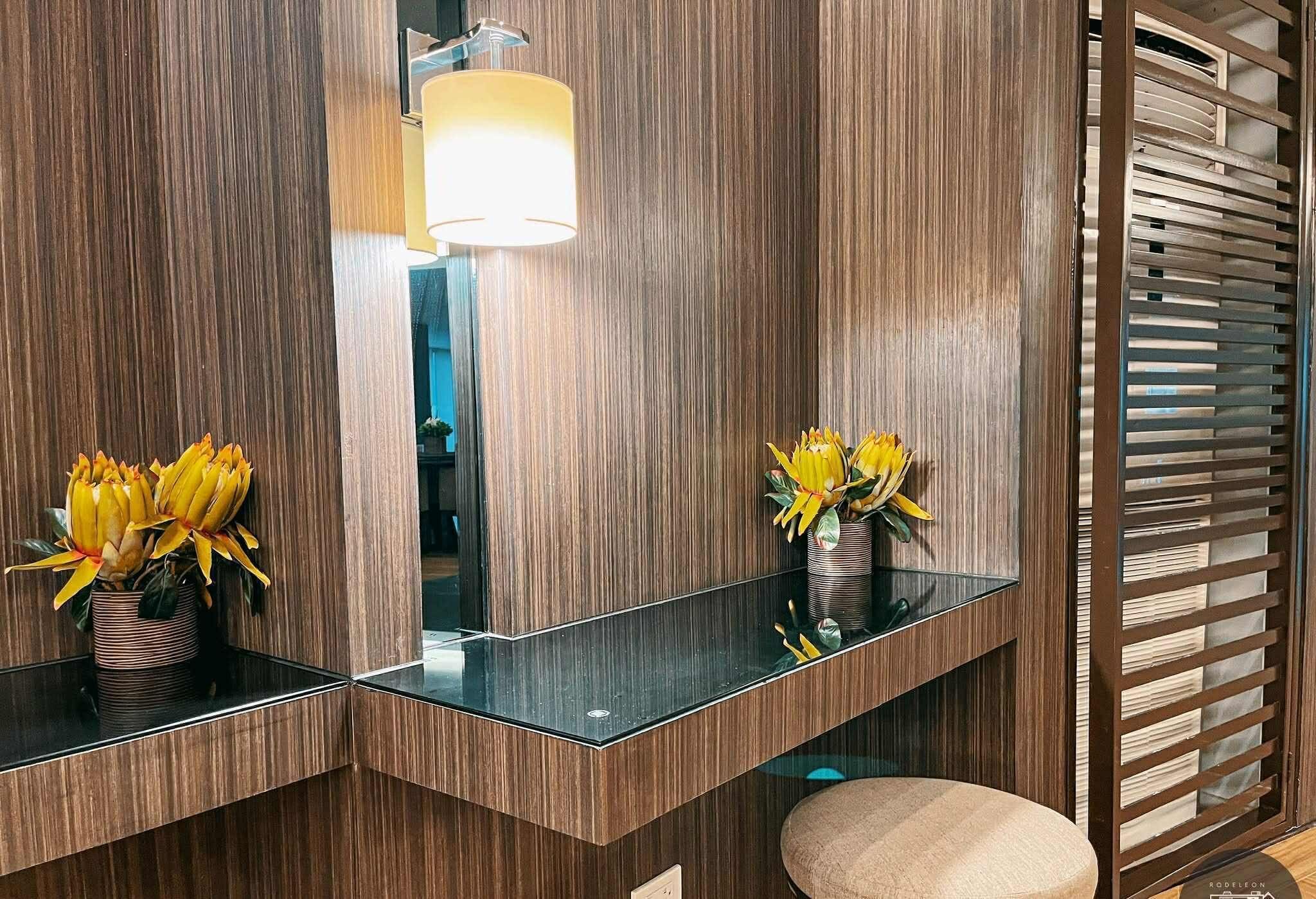 A modern bathroom with wooden paneling, a glass vanity, and a stool.