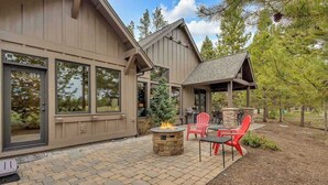 Une maison dotée d’un patio avec un foyer en pierre et des chaises rouges.
