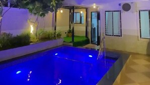 Un bâtiment moderne avec une piscine, de nuit.
