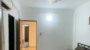 Une pièce avec un lit, un ventilateur de plafond et une porte donnant sur une autre pièce.