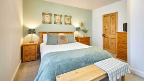 A bedroom with a bed, bedside tables, a wooden wardrobe, and a ceiling light fixture.