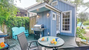 Una casa azul con una terraza, asientos exteriores y una parrilla.