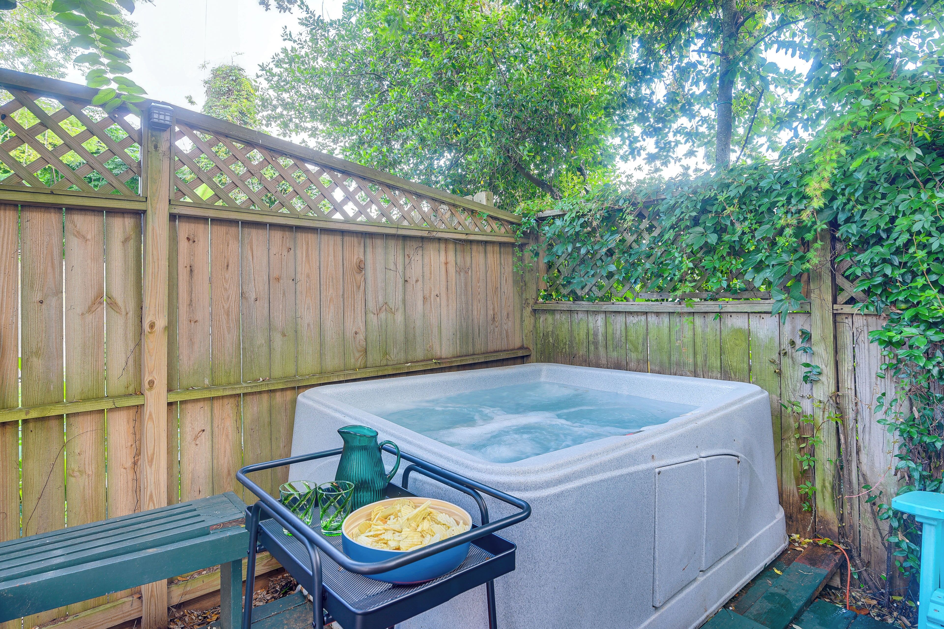 A hot tub with a wooden fence and greenery in the background.