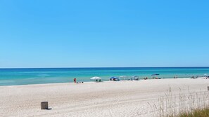 A wide sandy beach with clear blue water, several beach umbrellas, and a few people. - Beautiful Coastal Chic Home for 9 + Neighborhood Pool in Panama City Beach (Panama City Beach)
