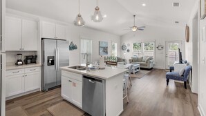 A spacious kitchen with white cabinetry, a central island, and a dining area with a white table and chairs. - Beautiful Coastal Chic Home for 9 + Neighborhood Pool in Panama City Beach (Panama City Beach)