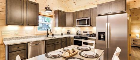 A modern kitchen with wooden walls, stainless steel appliances, and a dining area set for four.