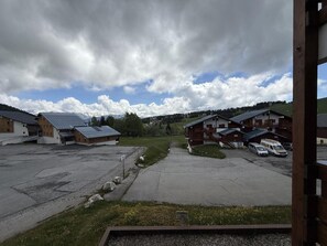 A parking area with several buildings, including a lodge with a wooden facade and a modern building with a sloped roof.