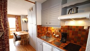 A compact kitchen with white cabinets, a tiled backsplash, a sink, a coffee maker, and a dishwasher. - 150m from ski slopes, 2nd floor, view ski slopes, balcony, parking, tv, ski locker, 29m² (Les Saisies)