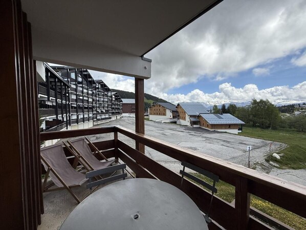 A balcony with a view of a parking lot, buildings, and mountains.