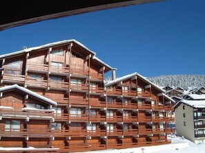 Un immeuble en bois à plusieurs étages, doté de balcons, qui ressemble probablement à un hôtel ou à un complexe touristique.