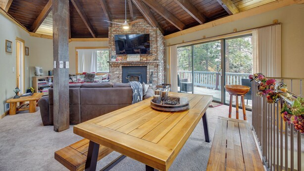 A spacious living area with a wooden ceiling, a stone fireplace, a large TV, and a balcony with a railing. - Big Bear Cabin w/ Hot Tub < 3 Mi to Skiing! (Big Bear City)
